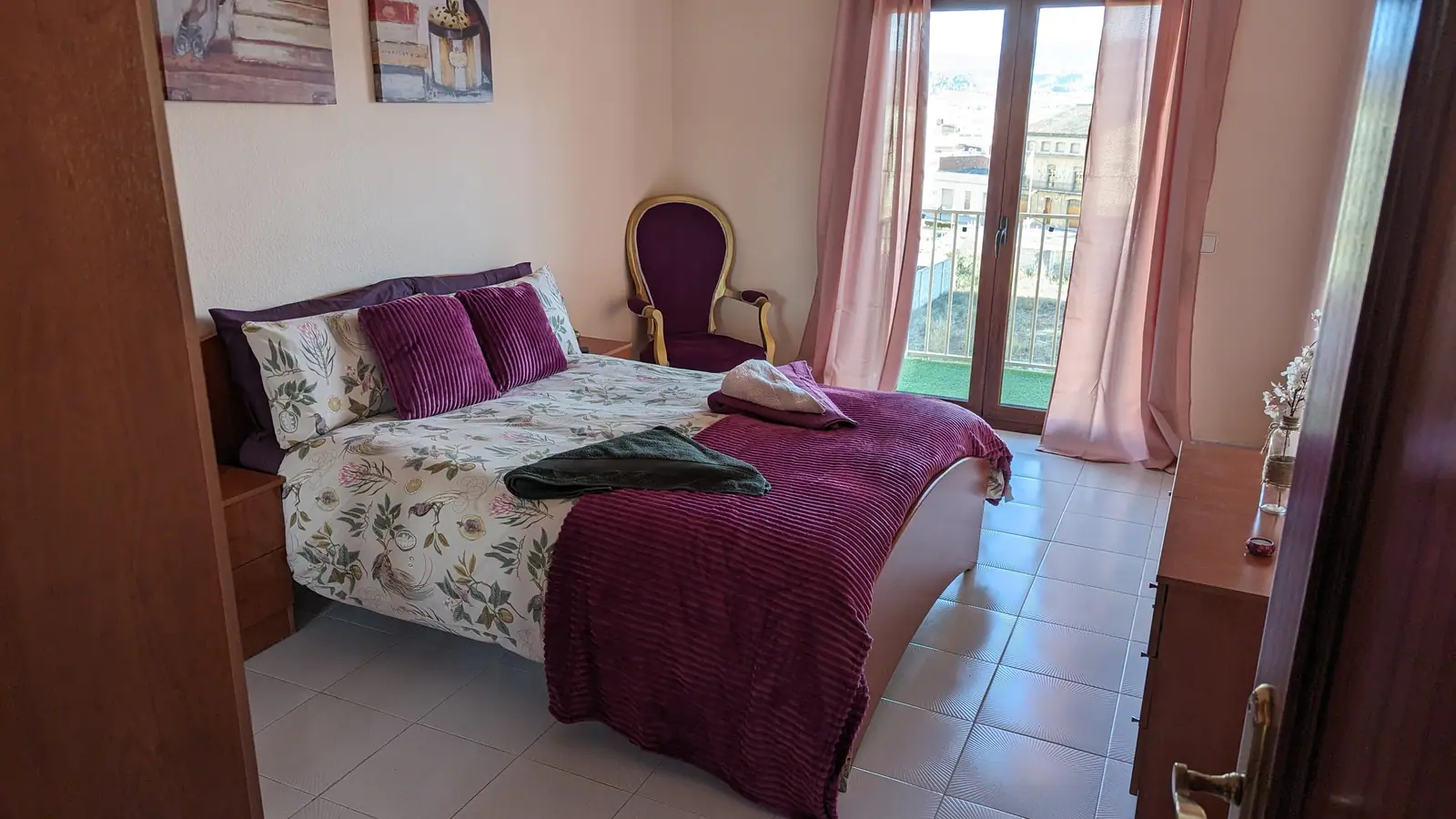 Double bedroom with burgundy bedding and doors onto a balcony