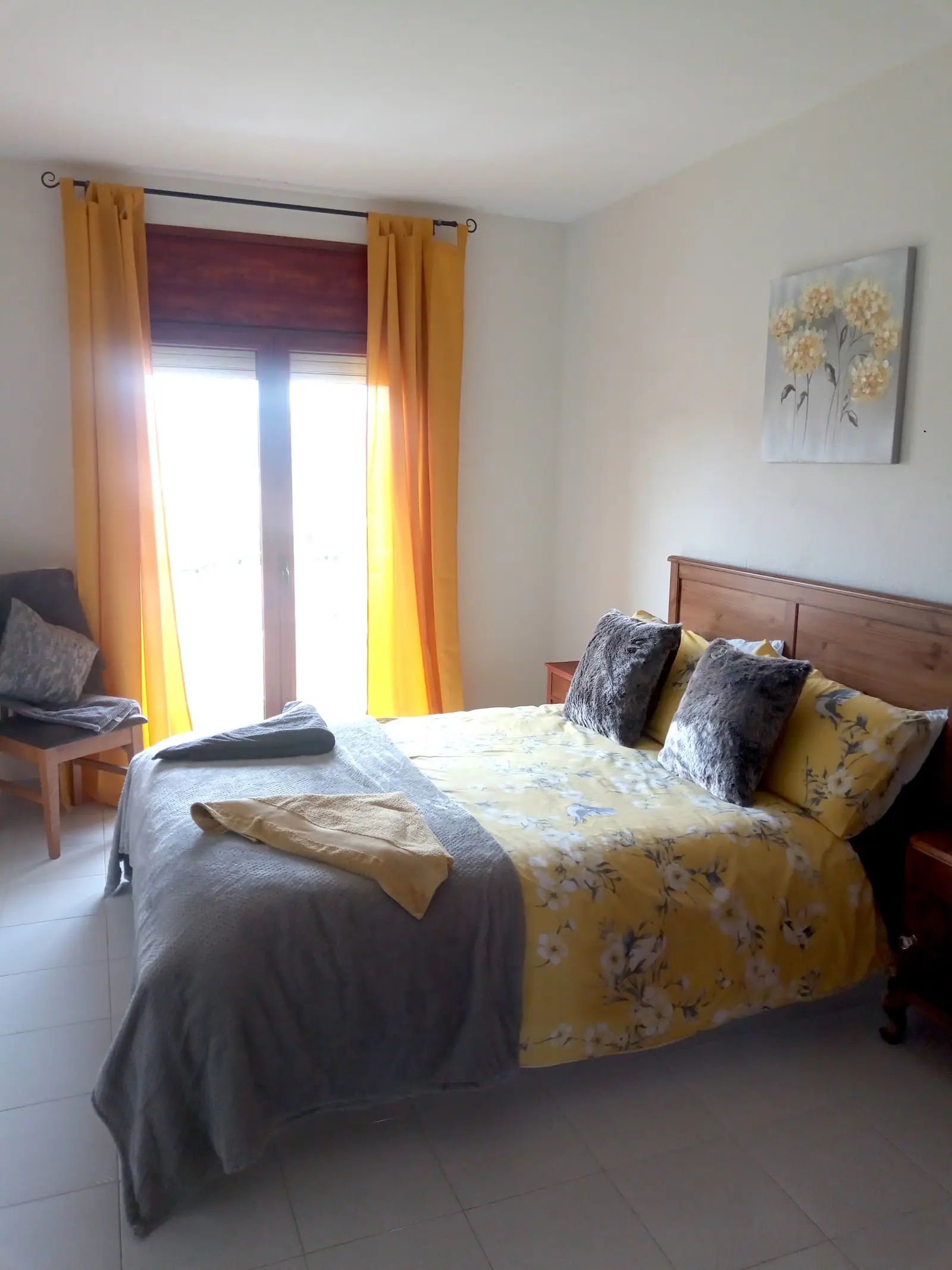 Double bedroom with tall windows and a seating chair