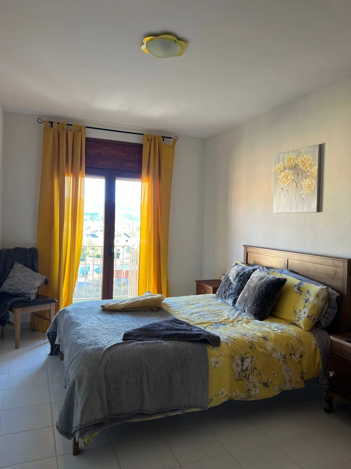 Double bedroom with yellow curtains and a balcony