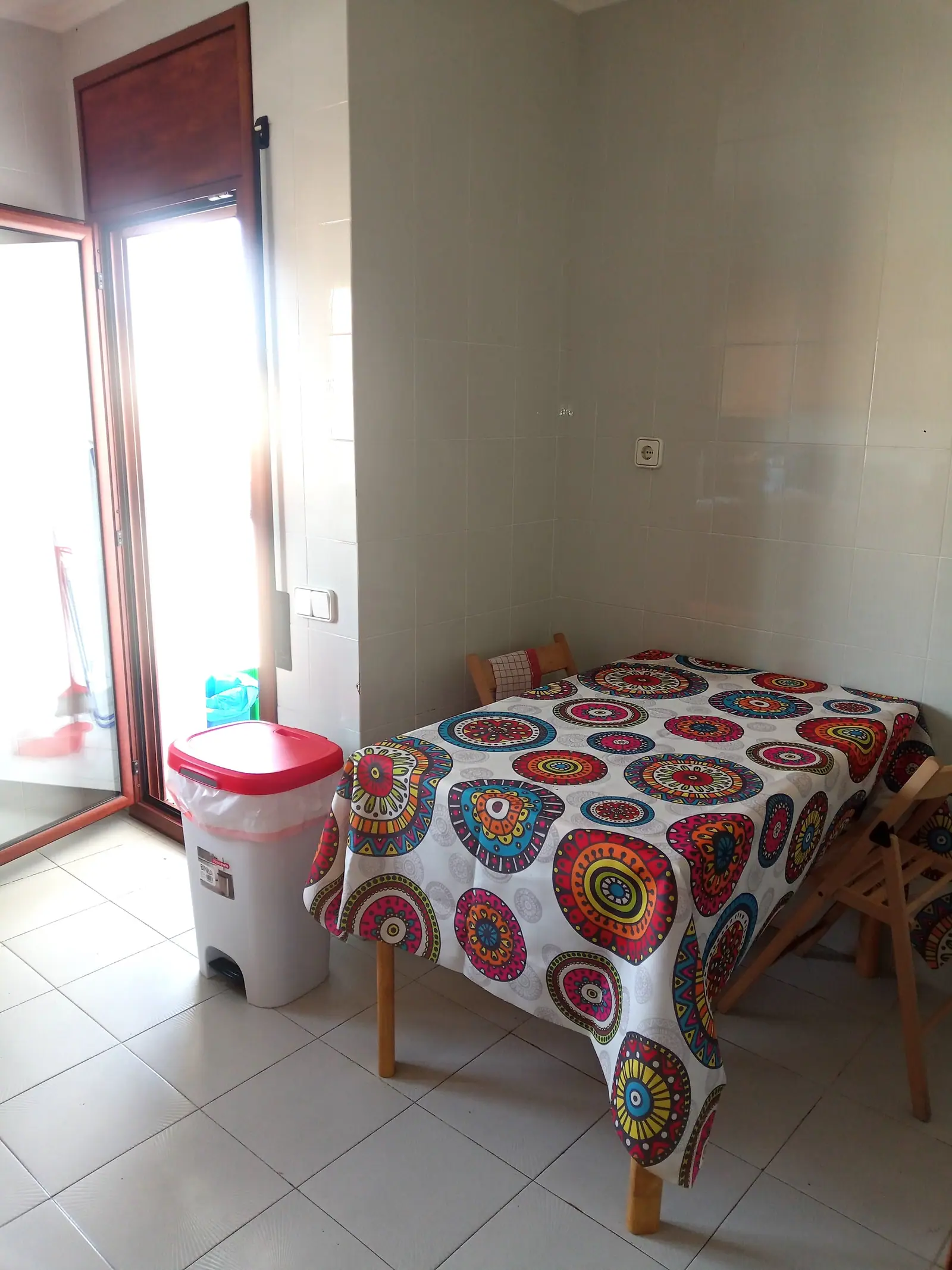 Utility room with a washing machine and a table beside the balcony door